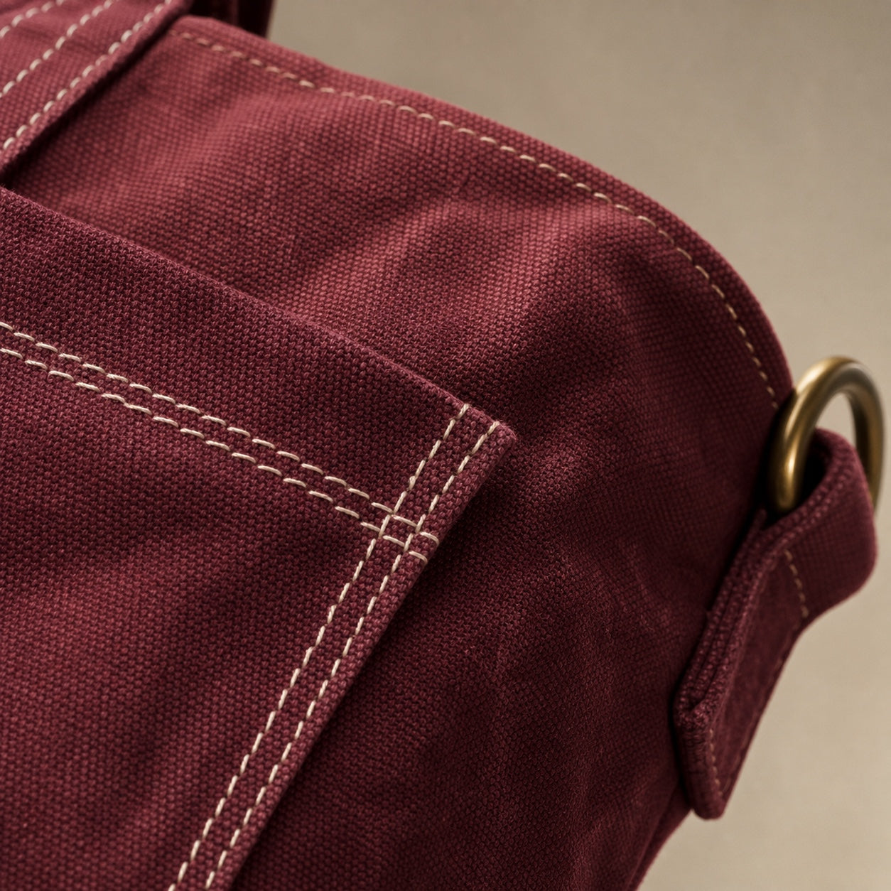 Close-up of oxblood washed canvas, contrast stitching, and antique-brass hardware