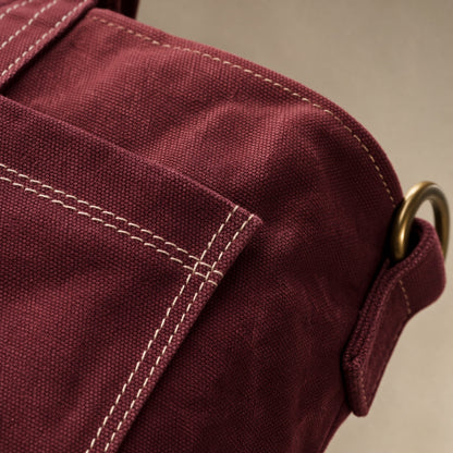 Close-up of oxblood washed canvas, contrast stitching, and antique-brass hardware