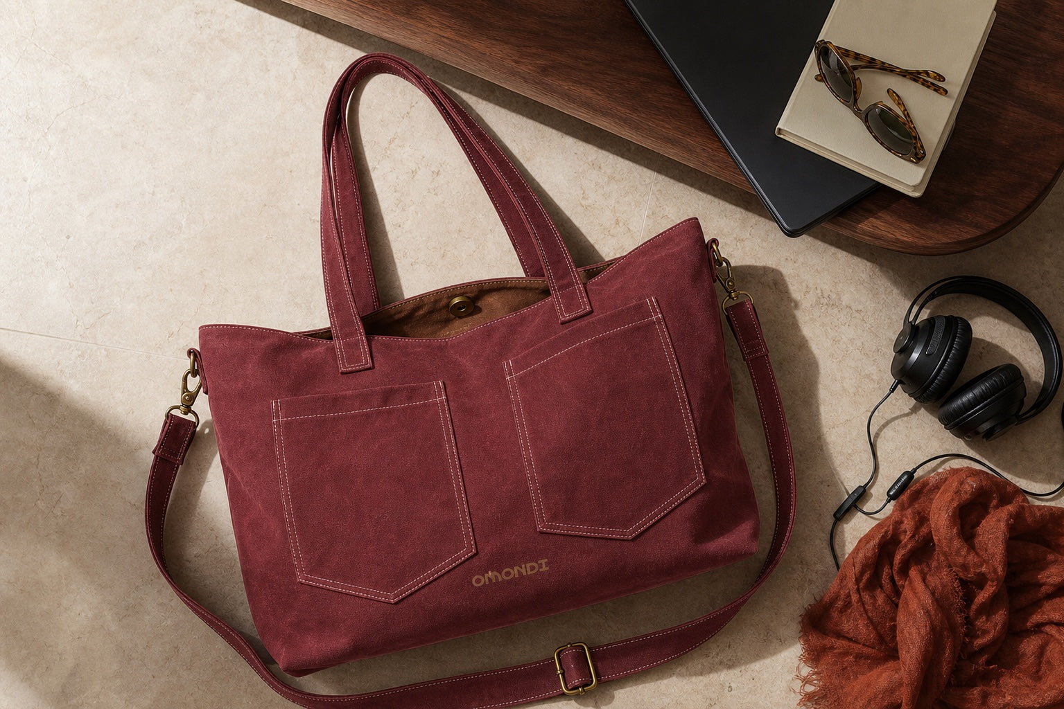 Overhead view of the oxblood OMONDI washed-canvas tote with everyday work and travel essentials