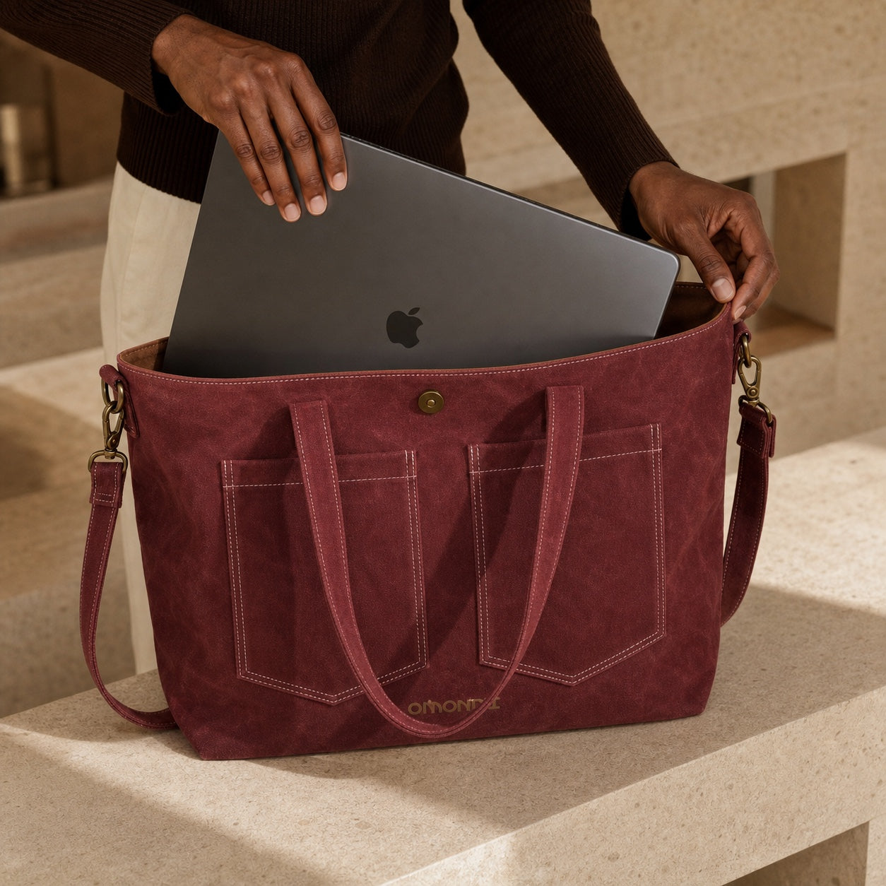 A 16-inch MacBook Pro being placed into the main compartment of the OMONDI washed-canvas tote